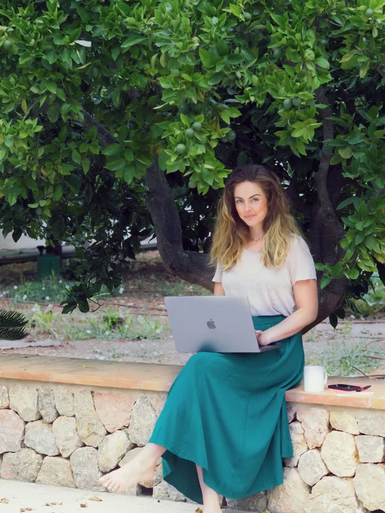 Spirituelles Webdesign von Matthea Adrienne, die in grünem Rock vor einem Orangenbaum sitzt